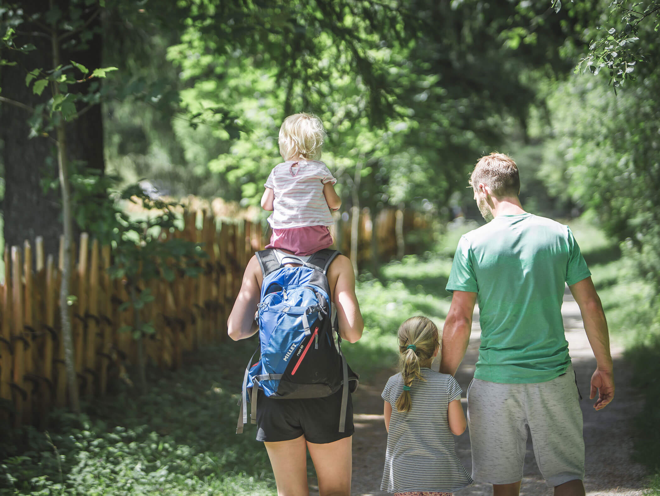 A family hiking - the mother carries a child on her shoulders, the father holds the other child by the hand - Knappenhof B&B