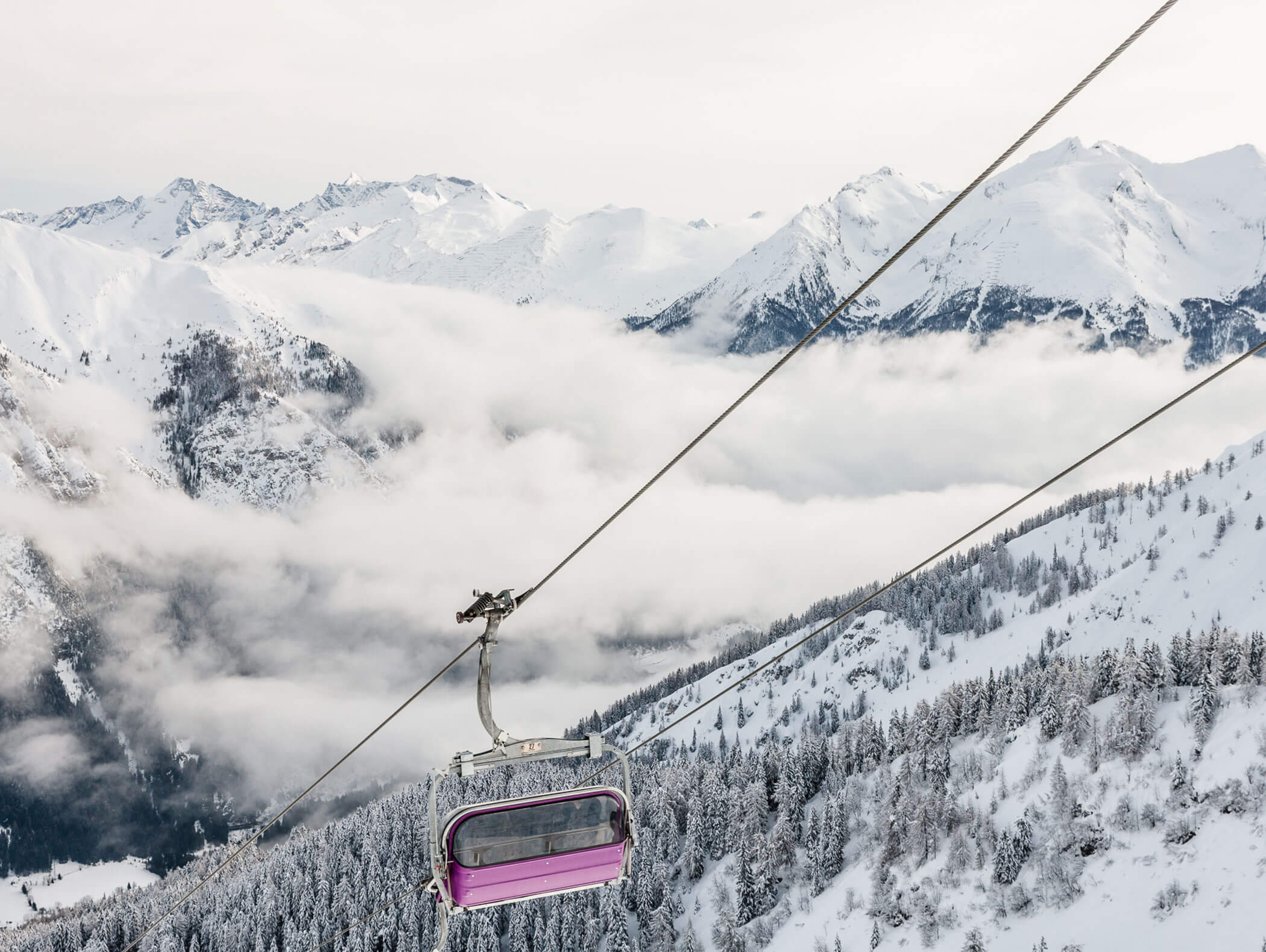 Pink chairlift from the Ladurns ski area travelling down the valley in winter - Knappenhof B&B